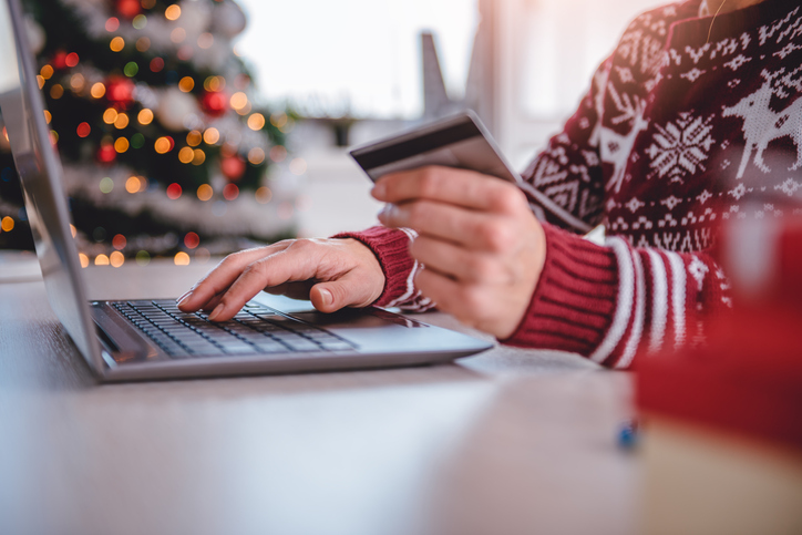 Women wearing red sweater shopping online and using credit card at home office