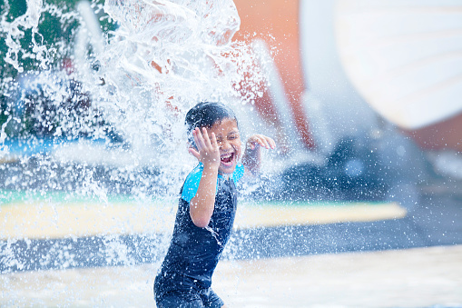 Little boy having fun with pool fountain.