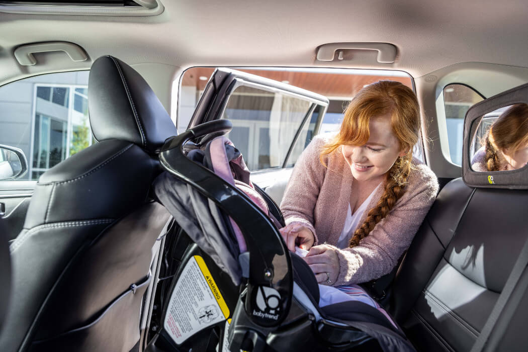 Woman strapping in a baby in a car seat